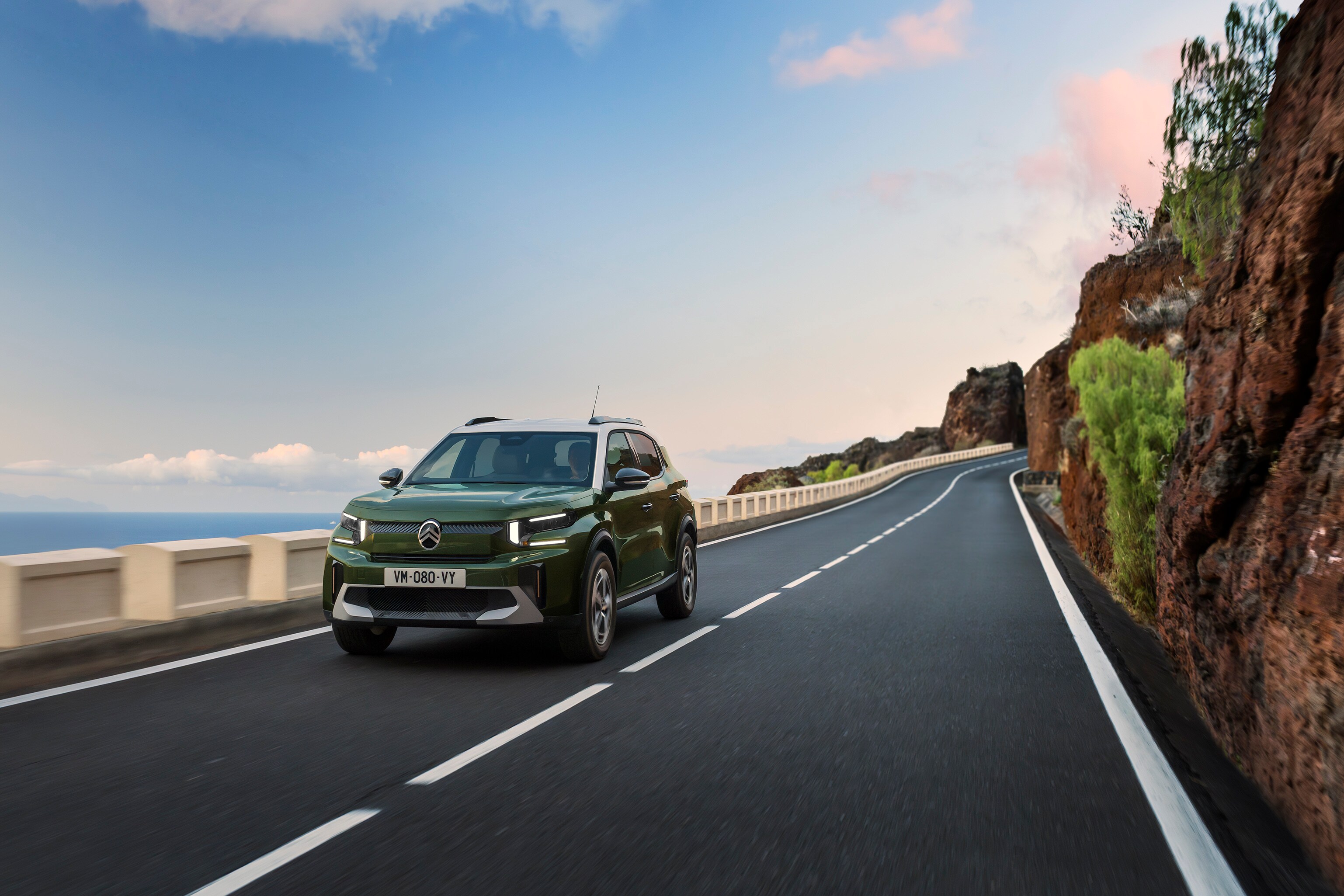 Vue avant trois quarts du SUV compact Citroën ë-C3 sur une route panoramique, mettant en valeur une mobilité quotidienne agile, confiante et abordable.