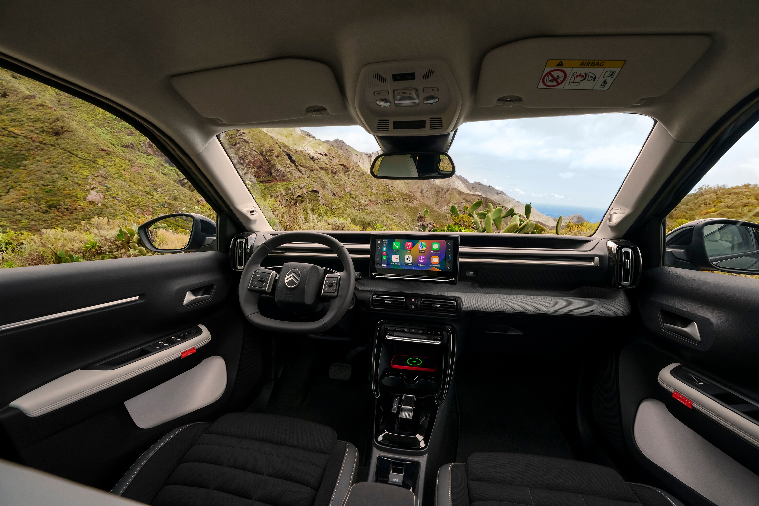 Vue intérieure frontale du SUV Citroën ë-C3 Aircross, avec tableau de bord panoramique et grand écran tactile pour une conduite intuitive, spacieuse et abordable au quotidien.